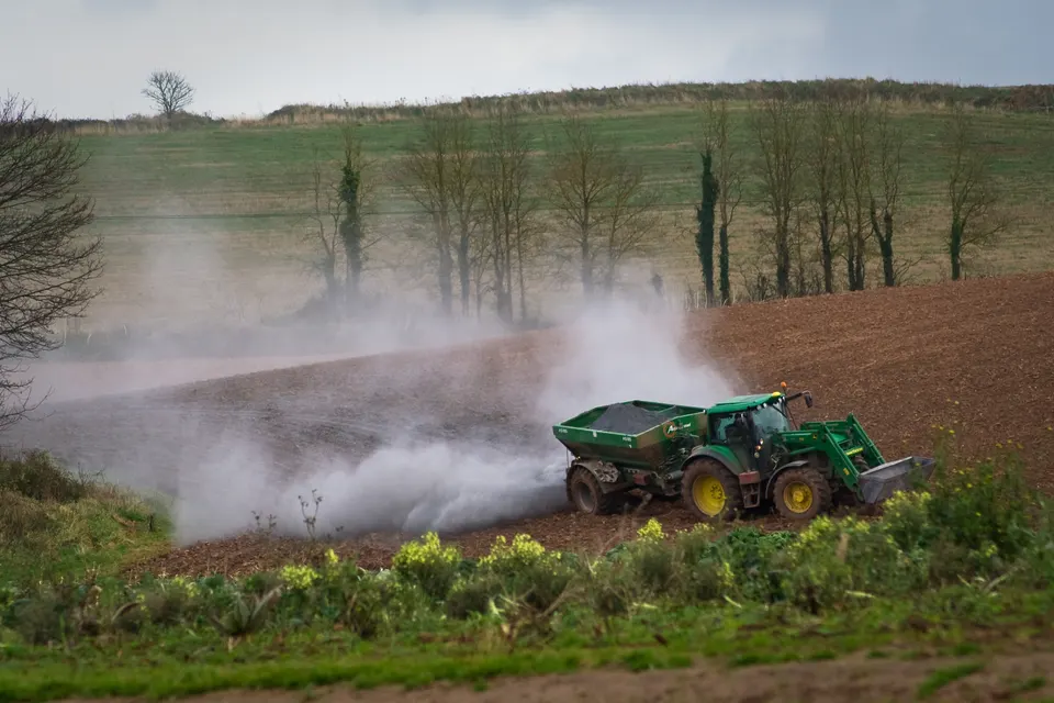 Tractor spreading agricultural lime across a field