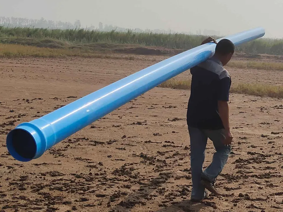 Worker carrying a long blue PVC pipe